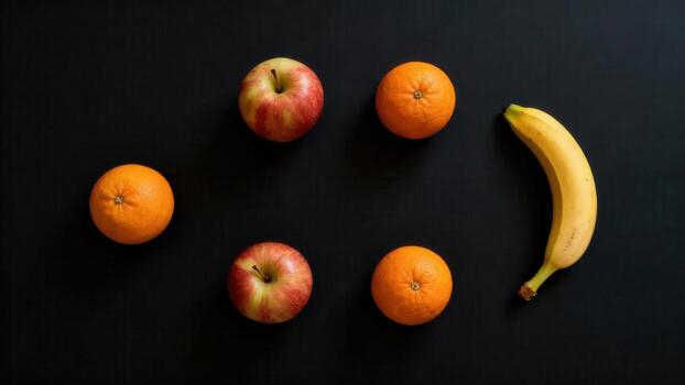 Assortment of fresh fruits including apples, oranges, and a banana arranged on a dark surface photo