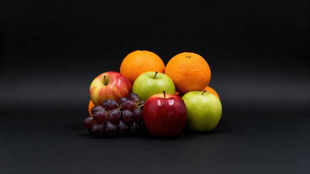 Pile of fresh assorted fruits rests against a solid dark background photo