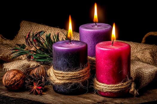 Three lit candles in shades of purple and red sit on a rustic wooden surface. They are tied with twine and surrounded by natural elements like pine and nuts, creating a cozy feel photo