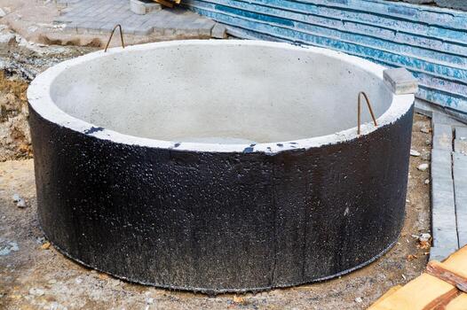 Installation of concrete sewer wells in ground at the construction site. The use of reinforced concrete rings for cesspools, overflow septic tanks. photo