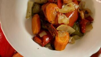 arrostito verdure riposo nel piatto, mostrando struttura e contrasto nel caldo toni. circondato di cipolle e peperoni, verdura colori creare rustico armonia. concetto di verdure come fusione rituale. video