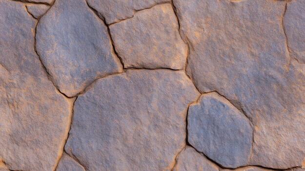 A close-up view of a textured stone surface, showcasing a pattern of irregular, polygonal shapes with deep crevices and varied shades of gray and brown. photo