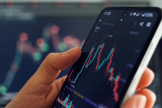 A person analyzes stock market data on a smartphone with colorful graphs displayed, set against a financial trading background photo