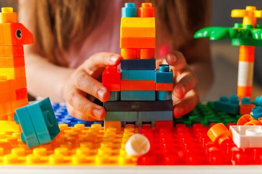 Hands build a colorful structure with toy blocks on a baseplate, showing creative construction, play, and childhood development. photo
