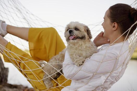 Woman relaxing with a dog in a hammock photo