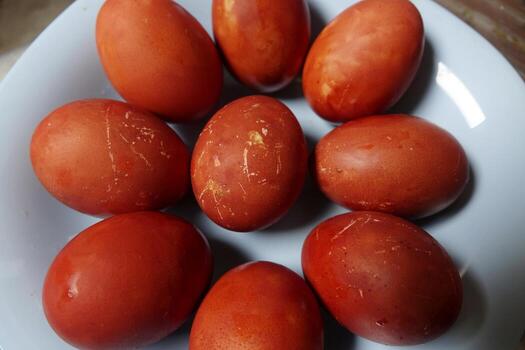 Plate is filled with numerous red Easter eggs with natural red-brown color and textured eggshells photo
