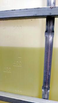 IBC containers filled with liquid show measurement markers in industrial setting at daytime photo