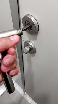 Handle Detached From the Door as a Person Attempts to Reattach It in a Residential Setting photo