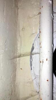 Cobwebs around a pipe in a dimly lit corner of a room photo