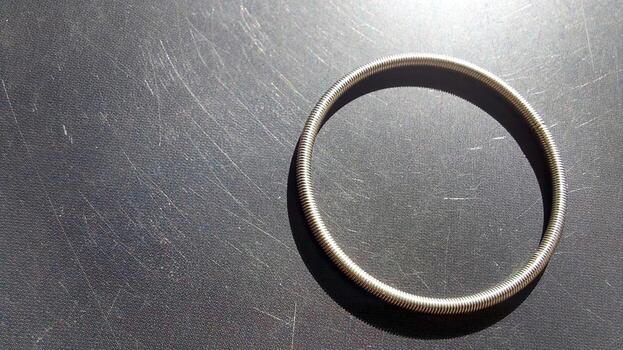 Round spring placed on a smooth surface reflecting sunlight creating beautiful shadows photo