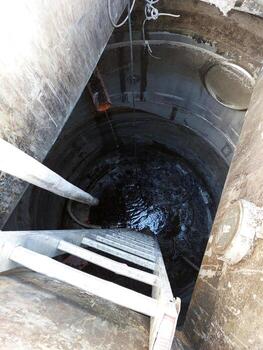 Exploring the Depths of an Urban Sewer Well With a Ladder Leading Into Darkness photo
