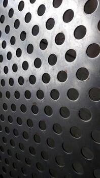Stainless Steel Mesh Displays Intricate Pattern of Perforations and Reflections in Bright Light photo