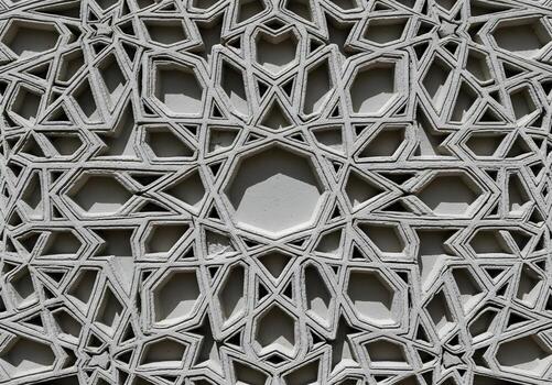 Intricate three-dimensional Islamic geometric pattern on a stone facade, showcasing detailed ornamentation and traditional Moorish design with strong shadows photo