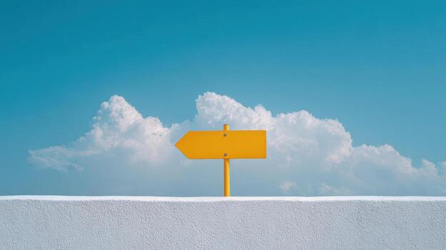 Bright yellow directional arrow sign mounted on a white wall, pointing to the right, with a backdrop of blue sky and fluffy clouds. photo