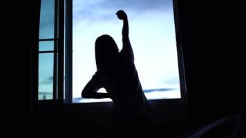 silhouette di persona allungamento di finestra, cattura la tranquillità e riflessione come morbido leggero migliora sereno atmosfera, evocando pace e calma durante bellissimo mattina routine video