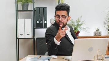 yo escoger tú. indio empresario programador software desarrollador trabajando en oficina ordenador portátil señalando a cámara, mirando con contento expresión, haciendo elección, demostración dirección. árabe persona de libre dedicación hombre video