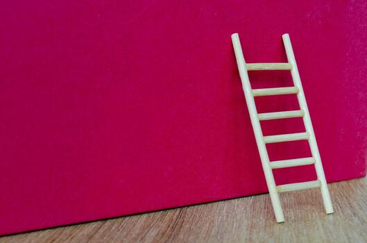 Side view of small ladder on dark red cover background with customizable space for text. photo