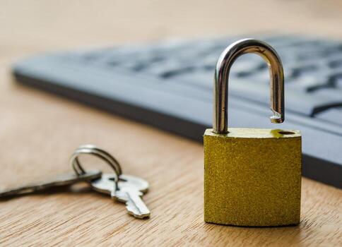 A small golden padlock standing open on a computer keyboard symbolizing cybersecurity breach and data protection risk concept. photo