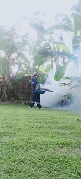 Pest control worker spraying insecticide to prevent mosquito bites during a hot summer day, environmental sanitation services photo