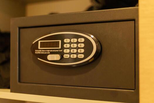 A digital safe sits in a wooden cabinet, equipped with a keypad for entering a unique code. It offers a secure place for storing personal belongings in a contemporary setting photo