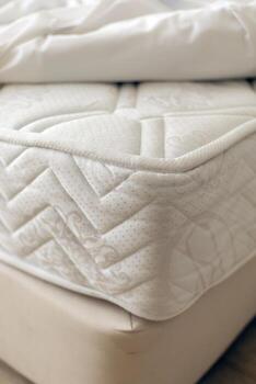 A plush mattress sits atop a soft bed frame, inviting relaxation. The soft bedding creates a warm and comfortable atmosphere, perfect for restful nights photo