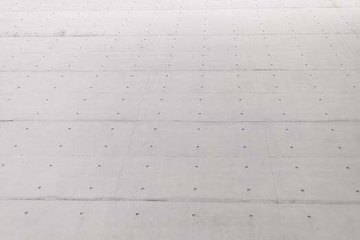 A close-up view of a concrete surface features evenly spaced holes. The setting suggests a construction area, illuminated by bright sunlight, highlighting the texture photo