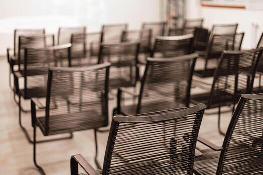 A spacious meeting room shows multiple rows of black chairs organized neatly for an upcoming event or presentation. The environment is calm and ready for attendees photo