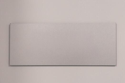 A blank rectangular signboard hangs on a plain wall, emphasizing a minimalistic design. photo