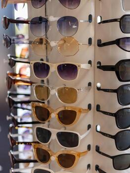 A selection of fashionable sunglasses is arranged on a display rack. The diverse styles include different shapes and shades, appealing to various tastes. Perfect for summer photo