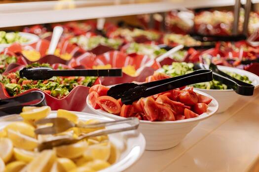 Colorful bowls filled with fresh vegetables, herbs, and fruits are arranged neatly on a buffet table. Guests can create their own salads with various toppings at lunchtime photo