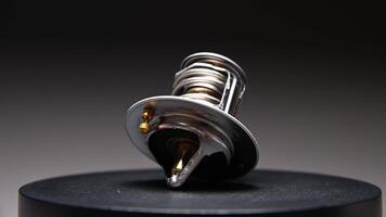 un' nuovo auto termostato su un' pendenza sfondo. il nuovo parte ruota con un' superficiale profondità di campo. video