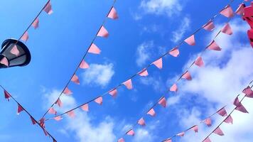 röd triangel- flaggor fladdra i de vind mot en ljus blå himmel. video