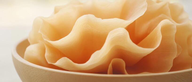 Thin pale layers curl inside shallow bowl. Close up delicate composition. Light brown edible slices. Wavy texture. Detailed image. photo