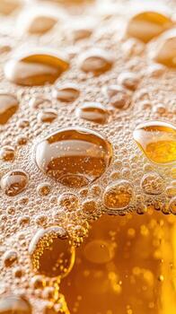 Golden liquid surface with bubbles and drops. Close up view of craft beverages texture. Bubbles float and reflect light. photo