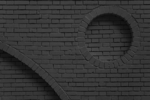 Brickwork with circular and arched elements made of black bricks. The photo captures an unconventional wall design where geometry serves as a decorative technique.