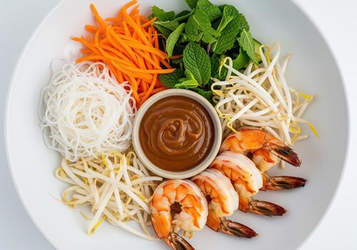 Deconstructed vietnamese shrimp spring roll bowl with noodles, fresh vegetables, and peanut sauce. photo