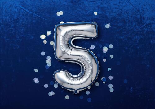 Metallic silver balloon number 5 centered on a vibrant blue festive background photo