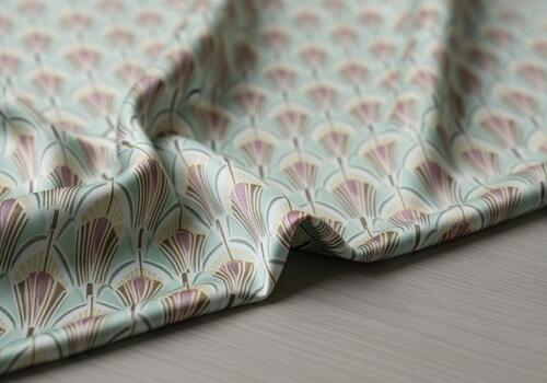 Luxurious charmeuse silk fabric draped with repeating art deco fan pattern in soft mint and mauve colors. photo