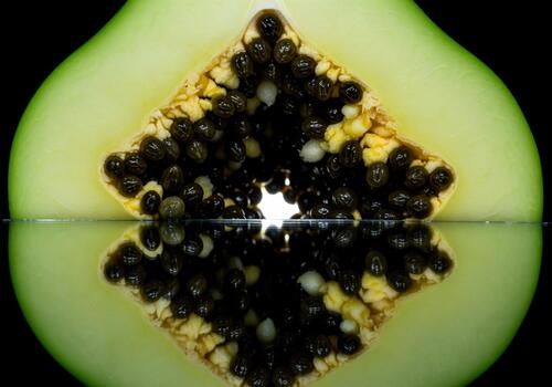 Abstract macro view of green papaya cross section revealing black seeds and reflection photo
