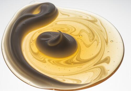 Abstract golden cosmetic gel and creamy lotion mixing in a beautiful swirl pattern photo