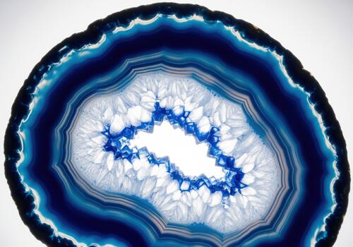 Abstract macro view of a vibrant blue agate slice showing translucent layers and quartz crystals. photo