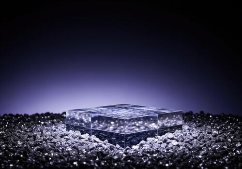 Crystal clear acrylic podium block resting on glittering dark gravel for product display photo