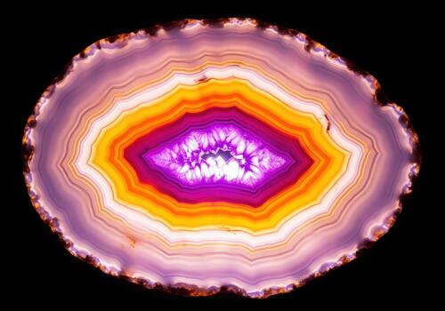 Vibrant purple and orange banded agate slice backlit showing crystalline geode structure. photo