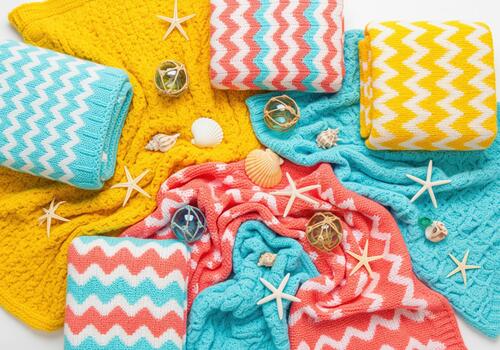Colorful knitted blankets with chevron pattern, starfish, and seashells, top view photo