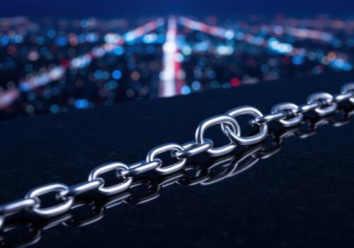 Gleaming silver metal chain links on a dark reflective surface with blurred city lights at night photo