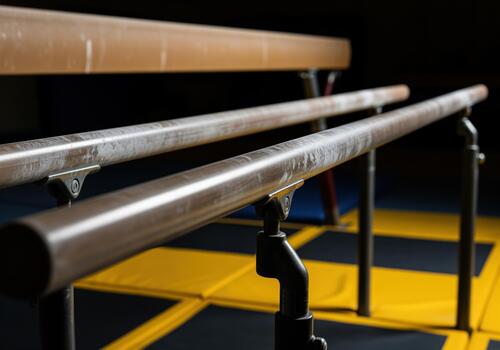 Close up of polished steel parallel bars in a dark gymnastics training gym setting. photo