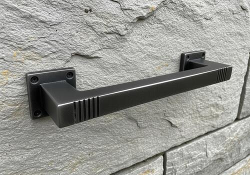 Modern dark metal pull handle hardware fixed securely onto a textured natural stone facade. photo