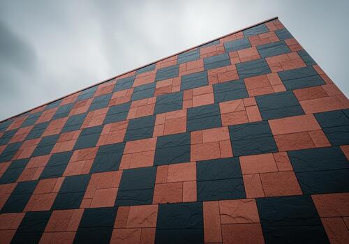 Striking geometric pattern on a modern building facade featuring contrasting red and black stone cladding. photo