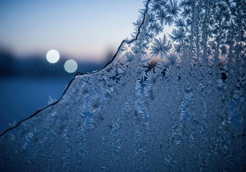 Close up of intricate ice crystal frost pattern forming on a window pane at dawn photo