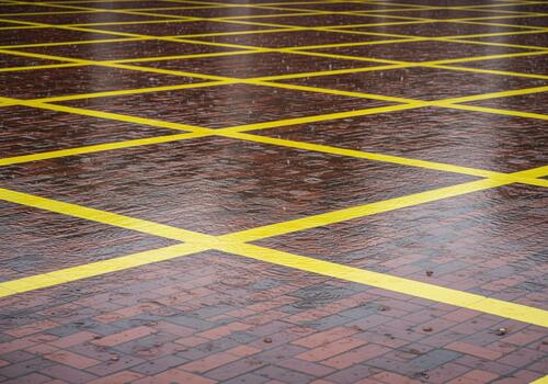 Yellow crisscross grid lines painted on wet red brick pavement during rain photo